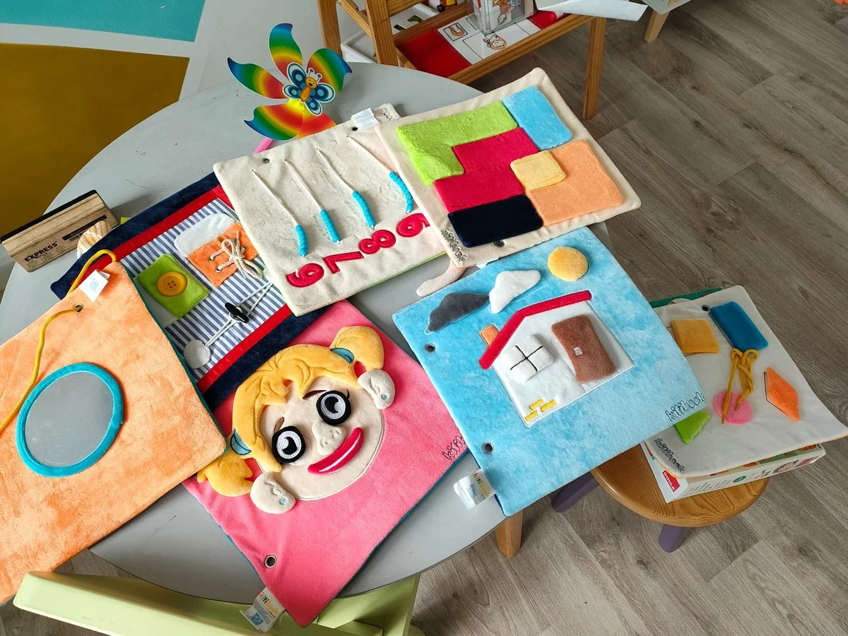 Détail des textures d'un livre sensoriel Kitibook — tissu brodé, scratch, boutons pour bébé 6 mois