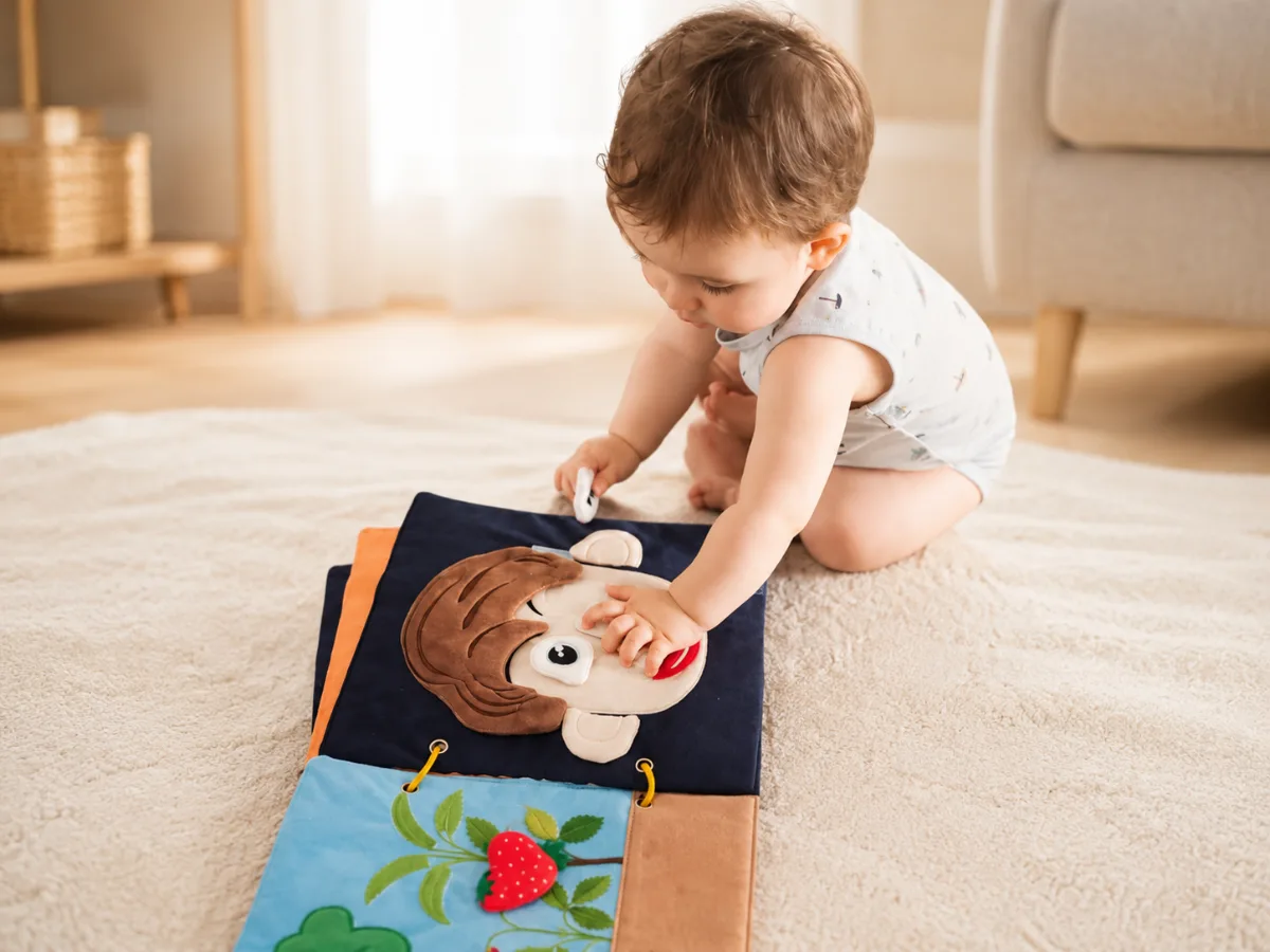 Livre sensoriel bébé en tissu Kitibook, bébé manipulant les planches à textures