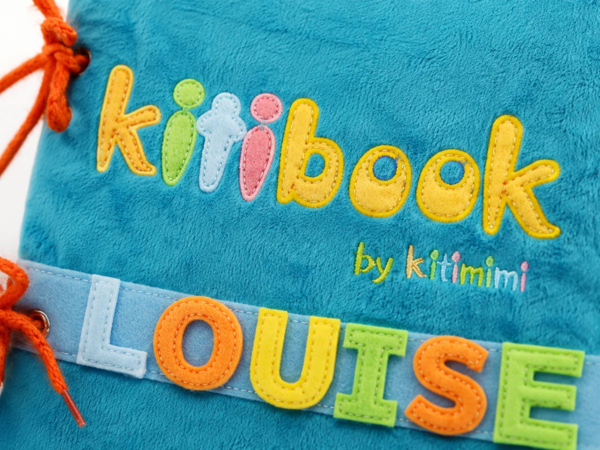 Gros plan sur le tissu et les coutures de la couverture Kitibook, lettres appliquées cousues